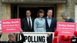 Britanski premijer i lider Konzervativne stranke Dejvid Kameron i njegova žena, Samanta, izlaze sa biračkog mesta u Spelzberiju u Engleskoj, dok su ispred birališta održani protesti. 