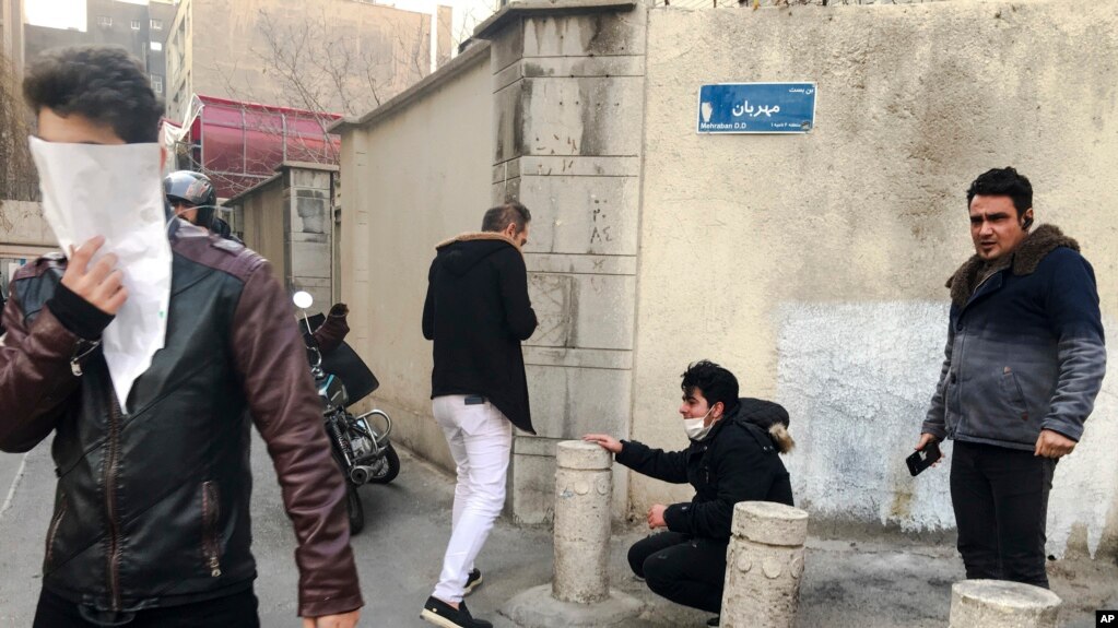 En esta foto tomada por un individuo no empleado por Associated Press y obtenida por la AP fuera de Irán, la gente reacciona al gas lacrimógeno disparado por la policía iraní en Teherán, Irán.  30 de diciembre de 2017