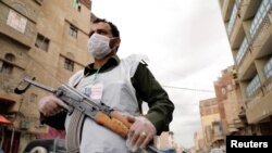 Seorang petugas keamanan mengenakan masker pelindung berjaga saat jam malam di tengah kekhawatiran penularan virus corona di Sanaa, Yaman, 6 Mei 2020.