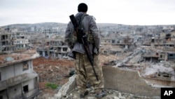 FILE - A Syrian Kurdish sniper looks at the rubble in the Syrian city of Kobani.