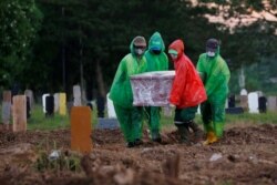 Para petugas membawa peti jenazah seorang dokter yang meninggal karena Covid-19, selama pemakaman di Jakarta.