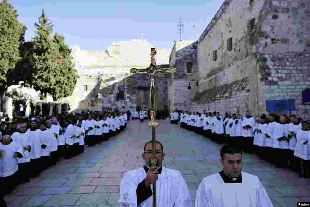 Seorang pastor memegang salib saat menunggu kedatangan Patriark Latin atau Uskup Agung Yerusalem Fouad Twal di luar Gereja Nativity (24/12).