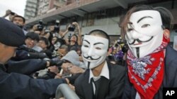 Pro-democracy demonstrators wearing Anonymous masks, scuffle with police during a protest against the Chinese government's meddling into the Hong Kong's chief executive election, in Hong Kong, April 1, 2012.