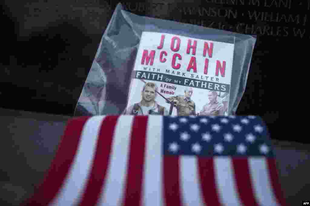 تصویری از کتاب سناتور فقید جان مک کین با عنوان &laquo;ایمان پدرانم&raquo; به همراه پرچم آمریکا در محل یادمان جنگ ویتنام در پایتخت آمریکا