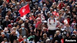 Demonstrators hold flags during a protest against Tunisian President Kais Saied's seizure of governing powers, in front of the parliament, in Tunis, Tunisia, Nov. 14, 2021.