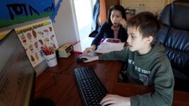 Kim Horrigan, left, sits with her son Conor Horrigan, as Conor does math homework at their home, in Quincy, Tuesday, April 13, 2021