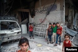 Children are seen near rubble of damaged buildings in the Damascus suburb of Eaterm Ghouta, Syria, July 17, 2017.