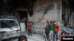 Children are seen near rubble of damaged buildings in the eastern Damascus suburb of Ghouta, Syria, July 17, 2017.