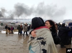 A couple embraces as opponents of the Dakota Access pipeline leave their main protest camp, Feb. 22, 2017, near Cannon Ball, N.D., as authorities were preparing to shut down the camp in advance of spring flooding season. The Army Corps of Engineers ordered the camp closed at 2 p.m. Wednesday.