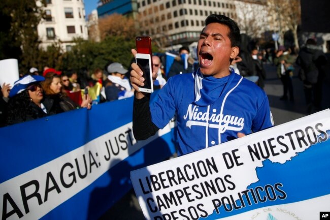 A demonstrator shouts slogans behind a banner reading in Spanish: "Release of our farmers Political prisoners" and "Nicaragua: Justice" during a protest against the Nicaraguan government in Madrid, Spain, Jan. 12, 2019.