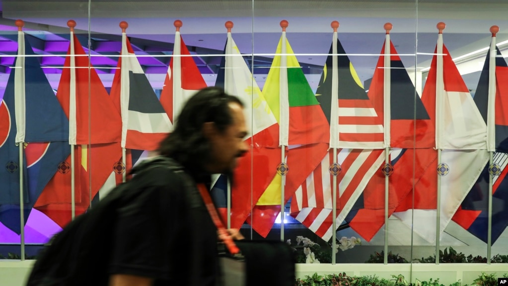 A journalist walks past ASEAN member country flags at the Suntec Convention Centre during the 33rd ASEAN summit in Singapore, Monday, Nov. 12, 2018. (AP Photo/Yong Teck Lim)