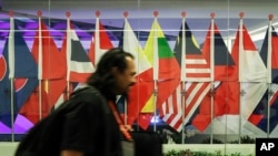 A journalist walks past ASEAN member country flags at the Suntec Convention Centre during the 33rd ASEAN summit in Singapore, Monday, Nov. 12, 2018. (AP Photo/Yong Teck Lim)