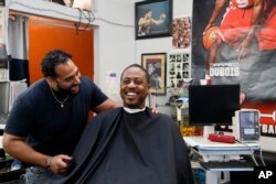 Barber Eric Muhammad, owner of A New You Barbershop, left, jokes with regular customer Marc M. Sims before measuring his blood pressure in Inglewood, California, March 11, 2018.