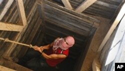 A Palestinian smuggler uses a rope to climb out of a tunnel linking the southern Gaza Strip town of Rafah with Egypt, 10 Dec 2009