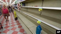 Shoppers pass empty shelves along the bottled water aisle in a Houston grocery store, Aug. 24, 2017.