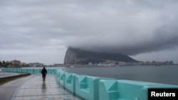 A pedestrian walks along the seafront in front of the Rock of Gibraltar as seen from La Linea de la Concepcion, Spain, Nov.22, 2018. 