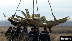 FILE - A crane transports a piece of the Malaysia Airlines flight MH17 wreckage at the crash site in eastern Ukraine's Donetsk region, Nov. 20, 2014.
