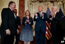 President Donald Trump applauds Secretary of State Mike Pompeo during a ceremonial swearing in at the State Department, May 2, 2018, in Washington. From left, Pompeo, his son Nicholas Pompeo, his wife Susan Pompeo, Trump, and Vice President Mike Pence.