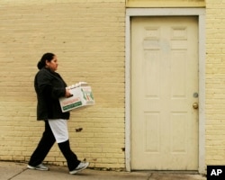 FILE -- Maria Reyes, originally from El Salvador, carries supplies into the La Pupusa Guanaca restaurant in the Jamaica Plain neighborhood of Boston, Massachusetts.