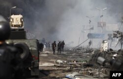 FILE - Egyptian security forces stand amidst remains of a protest camp by supporters of ousted civilian president Mohamed Morsi after a crackdown on August 14, 2013 near Cairo's Rabaa al-Adawiya square. Hundreds were killed by army-backed police.