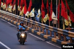 Seorang pengendara sepeda motor melewati jembatan layang yang dihiasi bendera-bendera partai politik menjelang pemilu, Jakarta, 6 April 2019. (Foto: Reuters)