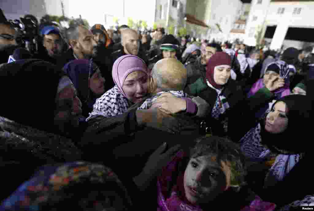 A prisoner released from an Israeli prison (C, back to camera) is welcomed by relatives in Ramallah, West Bank, Dec. 31, 2013. 