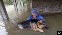 Joe Garcia carries his dog, Heidi, from his flooded home as he is rescued from rising floodwaters from Tropical Storm Harvey in Spring, Texas, Aug. 28, 2017.