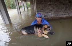 Joe Garcia carries his dog, Heidi, from his flooded home as he is rescued from rising floodwaters from Tropical Storm Harvey, Aug. 28, 2017, in Spring, Texas.