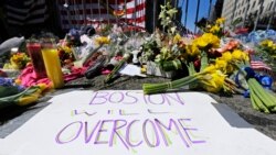 FILE - Flowers and signs adorn a barrier, two days after two explosions near the of finish line of the Boston Marathon at a makeshift memorial for victims and survivors, April 17, 2013.