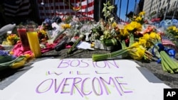 FILE - Flowers and signs adorn a barrier, two days after two explosions killed three and injured hundreds, at Boylston Street near the of finish line of the Boston Marathon at a makeshift memorial for victims and survivors, April 17, 2013. 