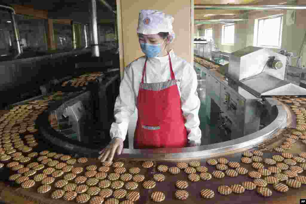 An employee monitors a cookie conveyor belt at the Unha Taesong Foodstuff Factory in Pyongyang, North Korea.