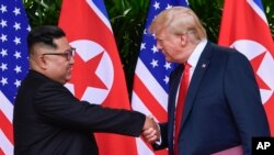 Kim Jong Un, dirigeant de la Corée du Nord, et Donald Trump, président des États-Unis, se serrent la main à l'issue de leur réunion au complexe Capella de l'île de Sentosa, le 12 juin 2018 à Singapour.