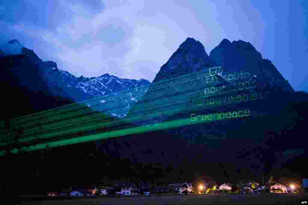 A handout photo released by Greenpeace shows a projection reading in French: &#39;G7 - Go for 100 percent renewables! Greenpeace&#39; on mountains near Elmau Castle, venue of the G7 summit, near Garmisch-Partenkirchen, southern Germany on the second day of the summit.