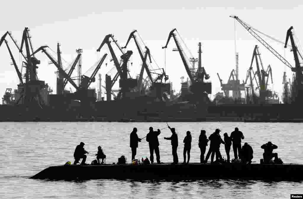 People fish on a pier at the port of Mariupol, located on the north of the Sea of Azov in eastern Ukraine.