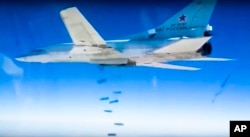 FILE - Russian Tu-22M3 bomber drops bombs on a target in photo made from video footage provided by the Russian Defense Ministry, Dec. 9, 2015.