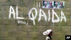 FILE - A girl walks past a wall with graffiti about the al-Qaida network in Kano, Nigeria, April 18, 2003. An airstrike this week by U.S. Africa Command targeted Al-Qaida in the Islamic Maghreb, near al-Uwaynat, Libya.