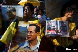 Well wishers hold a picture of Thailand's King Bhumibol Adulyadej as they gather with others outside the palace where he is staying in Hua Hin, Prachuap Khiri Khan province, during Coronation Day, May 5, 2014.