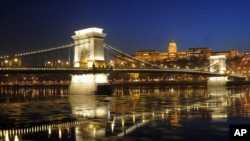 FILE - Ice-floes float under the floodlit Chain Bridge and the Royal Palace in the Castle of Buda in Budapest, Hungary.