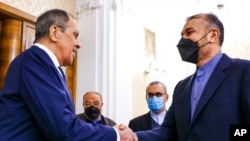 In this photo released by the Russian Foreign Ministry Press Service, Russian Foreign Minister Sergey Lavrov, left, shakes hands with Iranian Foreign Minister Hossein Amirabdollahian prior to their talks in Moscow, Russia, Jan. 20, 2022.