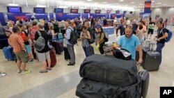 People push their bags as others stand in line after flights resumed Monday, Aug. 8, 2016, in Salt Lake City, following a computer outage. Delta Air Lines delayed or canceled hundreds of flights Monday after its computer systems crashed, stranding thousands of people on a busy travel day. (AP Photo/Rick Bowmer)