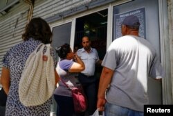 FILE - People ask for information to an employee at an office of state-owned airline Cubana in Havana, Cuba, June 7, 2018.