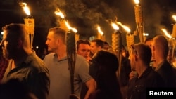 FILE - White supremacists carry torches on the grounds of the University of Virginia, on the eve of a planned "Unite the Right" rally in Charlottesville, Virginia, Aug. 11, 2017.
