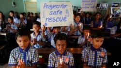 FILE - Students at a school in Ahmadabad, India, hold candles and pray for the Thai youth soccer players and their coach trapped in a cave, July 9, 2018.