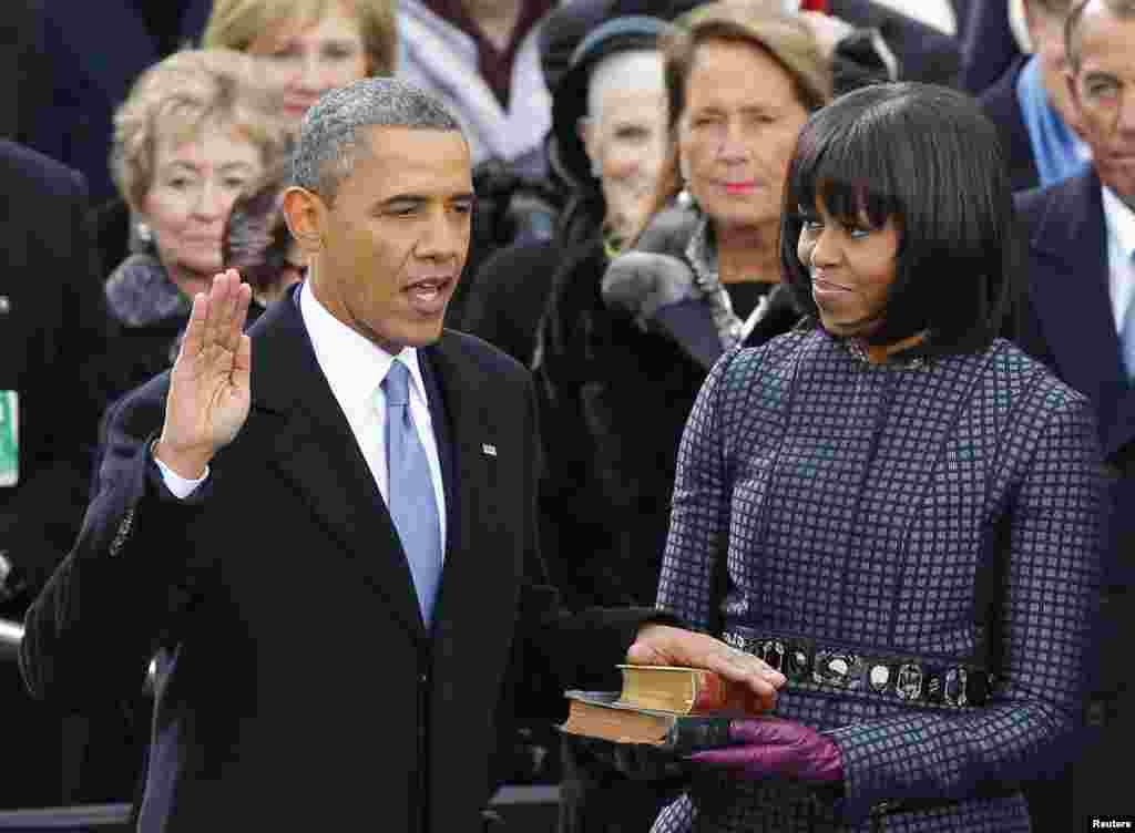 U.S. President Barack Obama recites his oath of office as first lady Michelle Obama looks on during swearing-in ceremonies on the West front of the U.S Capitol in Washington, January 21, 2013