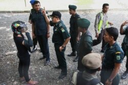 Seorang perempuan Aceh (kiri), yang sedang mengendarai motor, ditahan oleh polisi syariah karena mengenakan celana ketat tanpa hijab di Banda Aceh, ibu kota provinsi Aceh, 7 Mei 2014. (Foto: AFP)