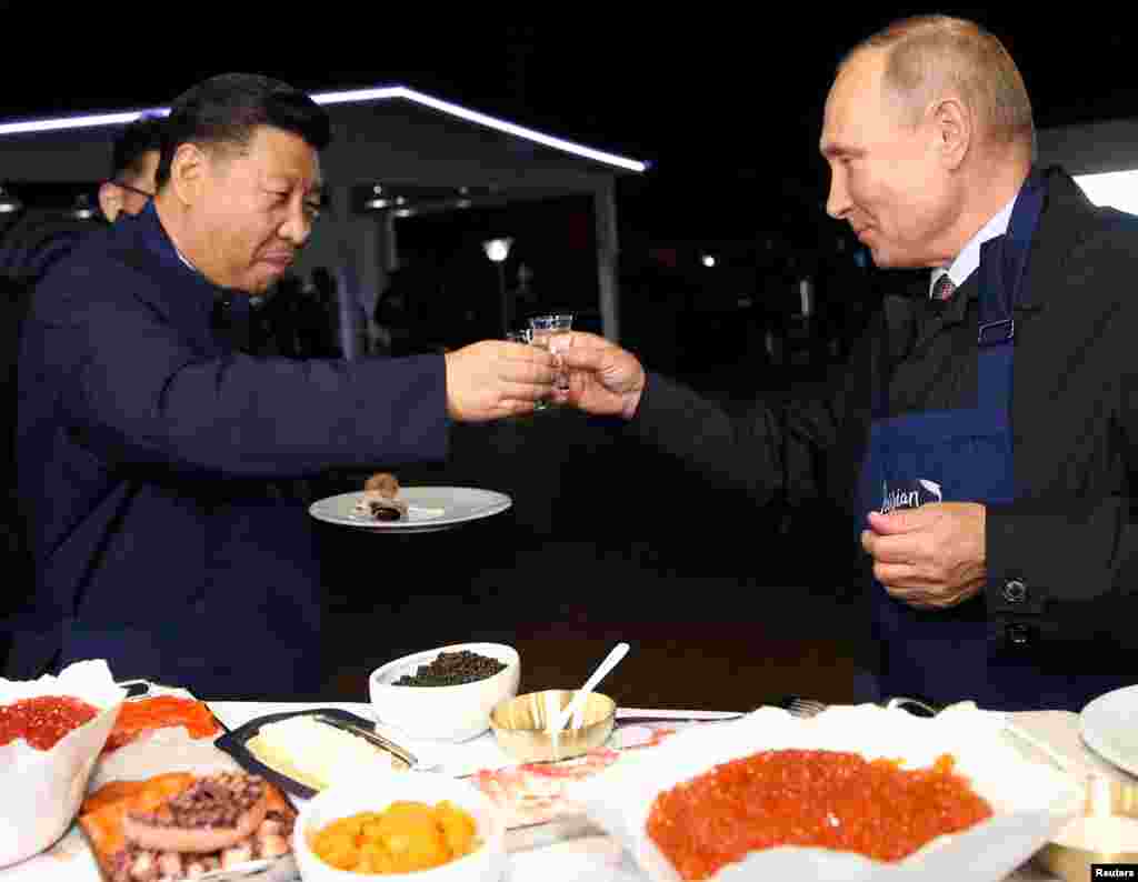 Russian President Vladimir Putin and Chinese President Xi Jinping toast during a visit to the Far East Street exhibition on the sidelines of the Eastern Economic Forum in Vladivostok, Russia.