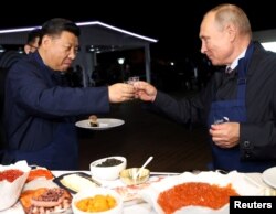 Russian President Vladimir Putin and Chinese President Xi Jinping toast during a visit to the Far East Street exhibition on the sidelines of the Eastern Economic Forum in Vladivostok, Russia September 11, 2018.
