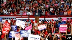 Para pendukung mengacungkan poster-poster berisi dukungan saat kampanye yang dihadi oleh Presiden Donald Trump di Pensacola, Florida, 3 November 2018.