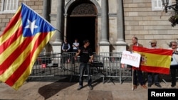 A man holding a Catalan separatist flag (L) looks at men holding a Spanish flag outside the Generalitat Palace, the Catalan regional government headquarters in Barcelona, Spain, Oct. 30, 2017.