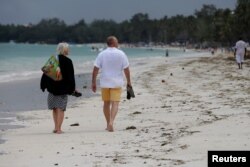 Tourists walk on a beach in Mombasa, Kenya, Aug. 5, 2017.